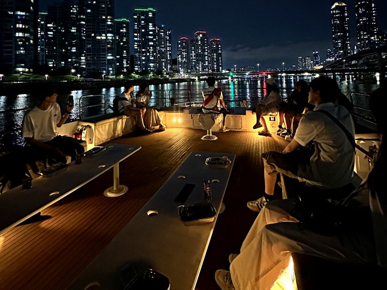 Group of guests on deck with the night view behind