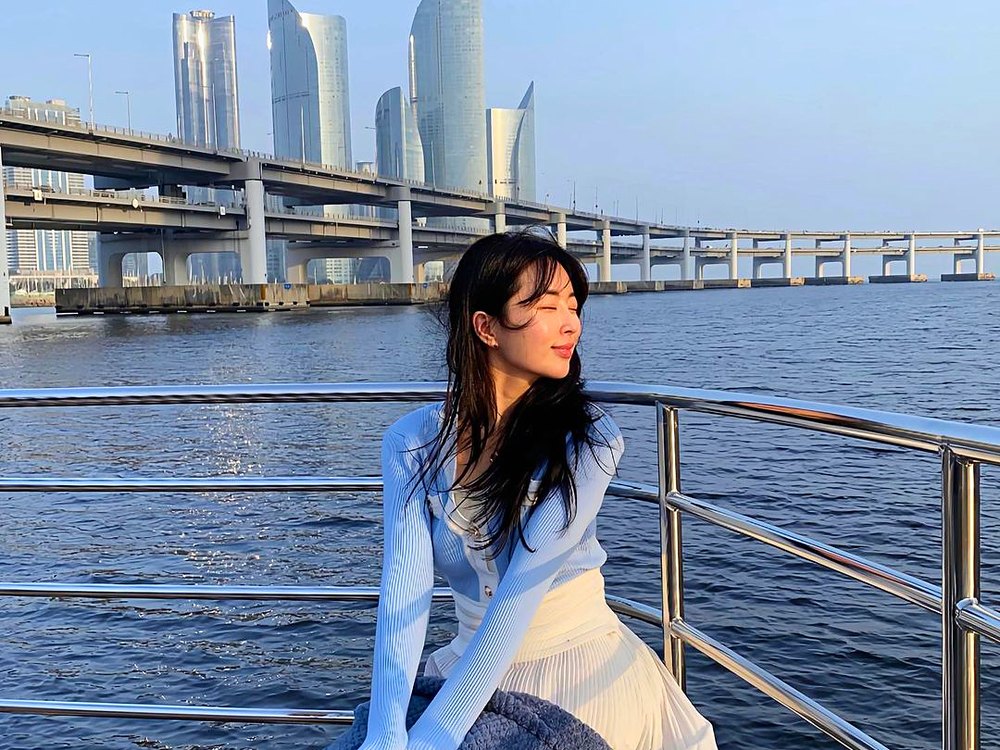 Guest sitting on the cruise railing with Gwangan Bridge and Marine City behind