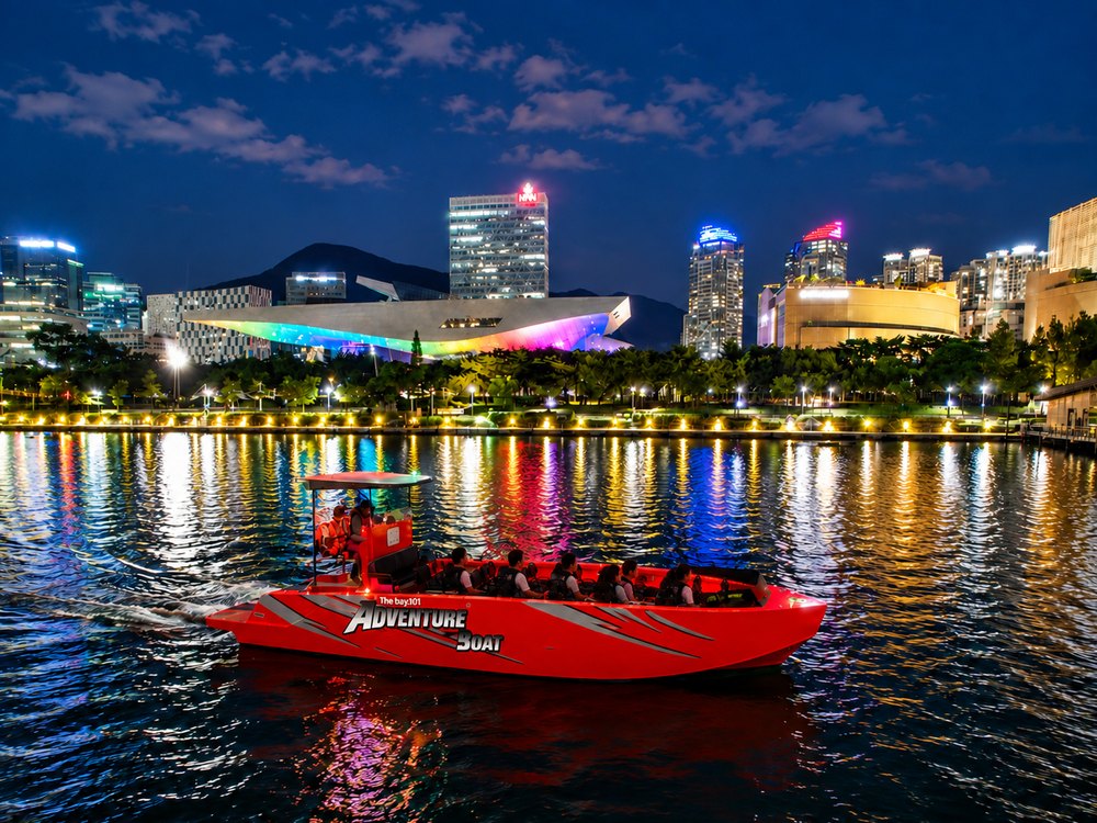 Adventure Boat on the night sea in front of the Marine City skyline